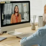 Schüler sitzt vor dem Computer und redet mit seiner Lehrerin