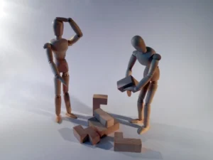 zwei Holzfiguren stehen vor einem Rätsel