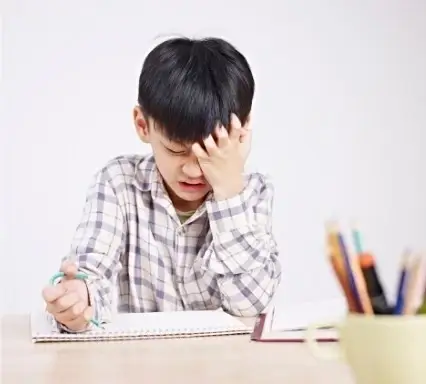 Junge sitzt am Schreibtisch und ist wegen Dyskalkulie frustriert.
