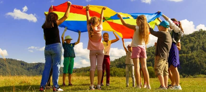 Gruppe von Menschen die eine bunt gegliederte Plane hochheben