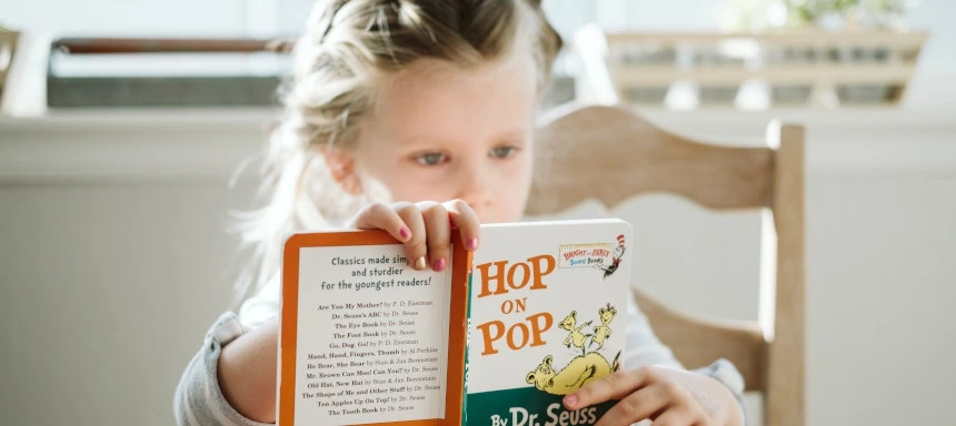 Kleines Mädchen, das das Buch "Hop on Pop" liest