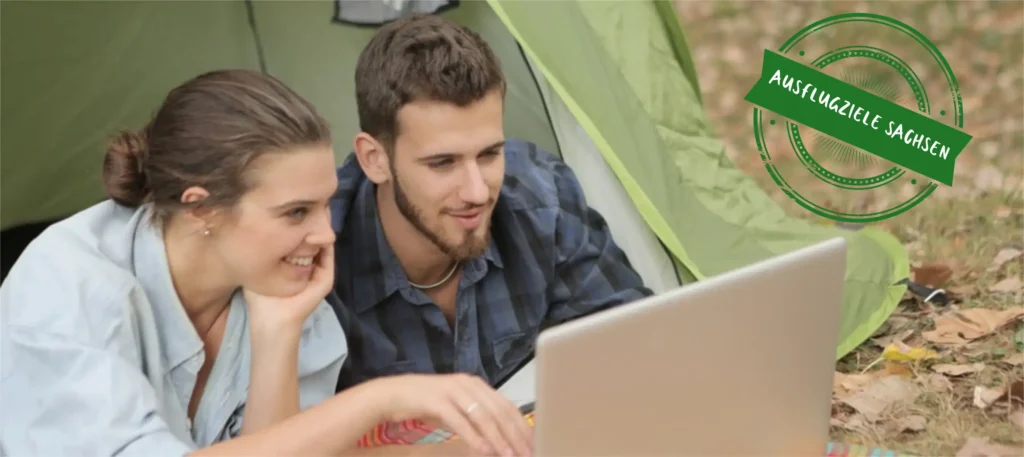 Mann und Frau schauen auf einen Laptop, recht steht Ausflugsziele Sachsen
