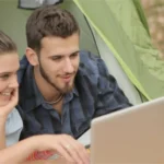 Mann und Frau schauen auf einen Laptop, recht steht Ausflugsziele Sachsen