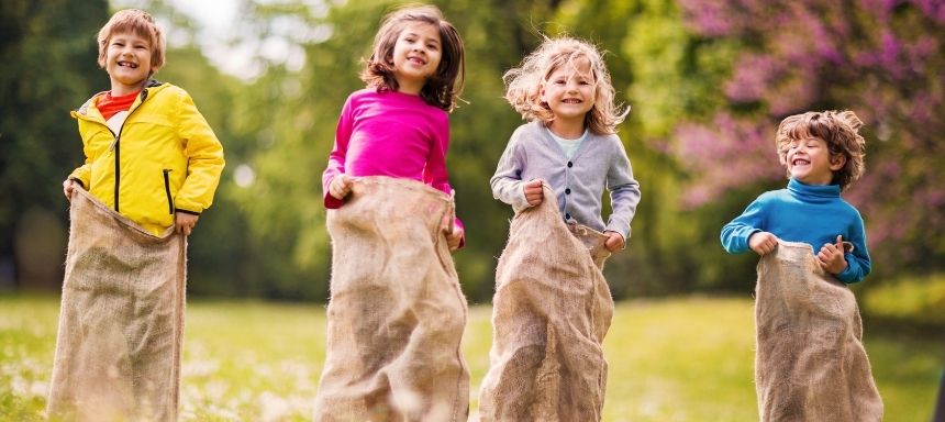 vier Kinder hüpfen gegeneinander in Säcken