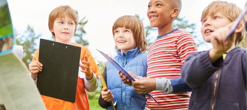 vier Kinder mit Klemmbrettern bekommen Anweisungen