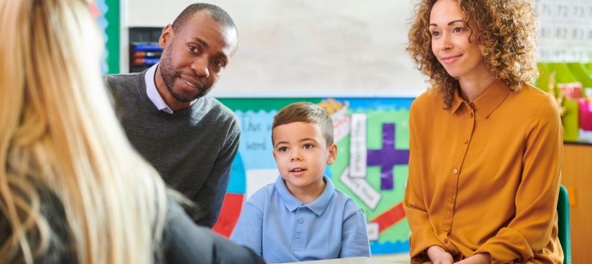 eltern mit kind in der Mitte reden mit Lehrerin