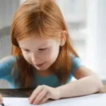 ADS Kinder: Ein Mädchen sitzt an einem Tisch und schreibt.