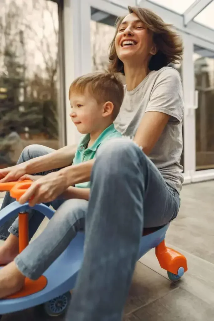 Mutter fährt mit Sohn Bobby Car und lacht als Symbol für die emotionale Beziehung zwischen Mutter und Kind.