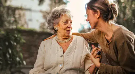 Eine ältere und eine jüngere Frau unterhalten sich und sind sich dabei körperlich nah.