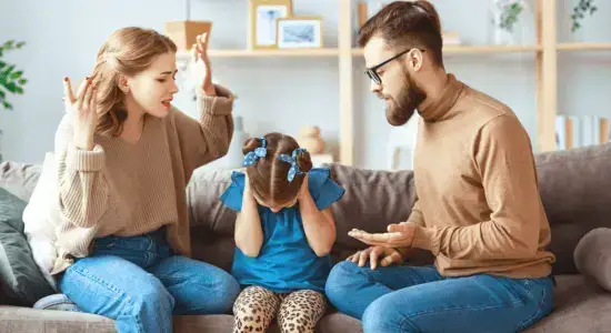 Eltern und Tochter sitzen auf einer Couch und streiten als Beispiel für eine unsicher-desorganisierte Bindung.