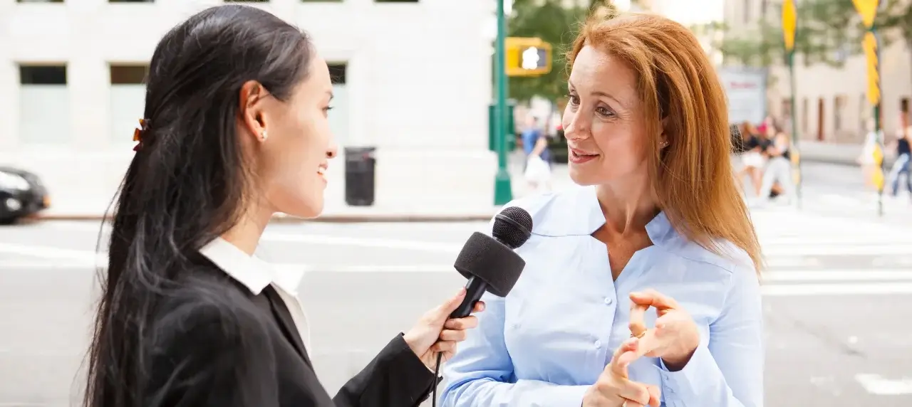 Zwei Frauen während einem Interview. Linke Frau hält Mikrofon, rechte Frau spricht in Mikrofon.